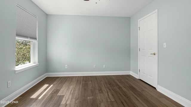 unfurnished room featuring dark wood finished floors, baseboards, and ceiling fan