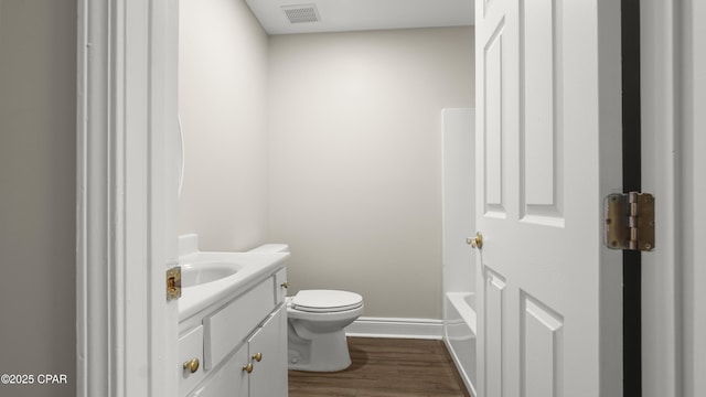 bathroom with wood finished floors, toilet, vanity, baseboards, and visible vents