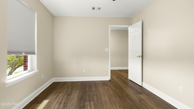 spare room with visible vents, baseboards, and dark wood finished floors