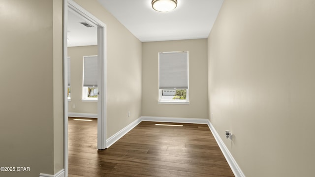 interior space with dark wood-style flooring, visible vents, a healthy amount of sunlight, and baseboards