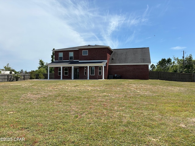 rear view of property featuring brick siding, fence, a yard, and a patio area