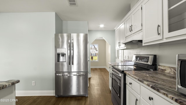 kitchen with dark wood-style flooring, under cabinet range hood, visible vents, baseboards, and appliances with stainless steel finishes