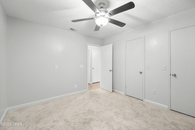 unfurnished bedroom featuring baseboards, visible vents, carpet, and ceiling fan