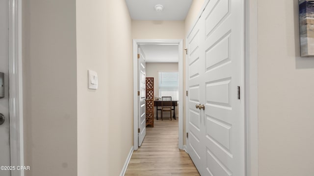 corridor featuring baseboards and light wood-type flooring