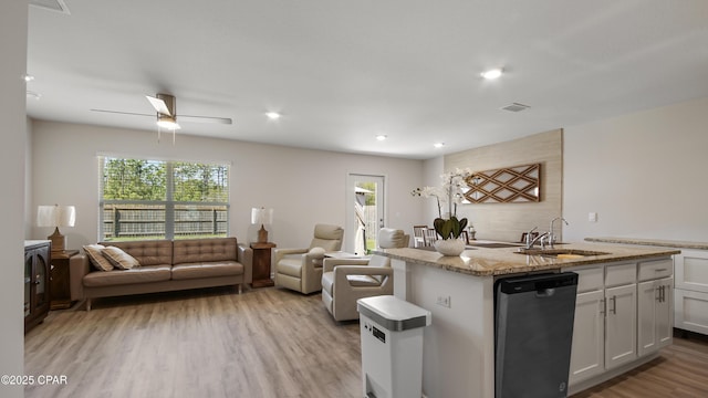 kitchen with a sink, dishwashing machine, a healthy amount of sunlight, and open floor plan