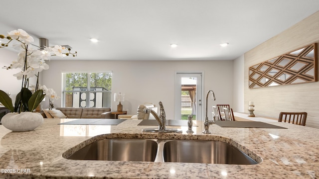 kitchen featuring light stone counters, a sink, and recessed lighting