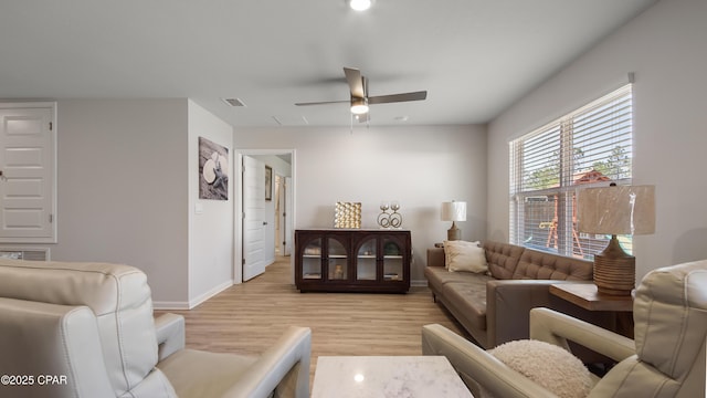 living room with baseboards, a ceiling fan, light wood-style flooring, and visible vents
