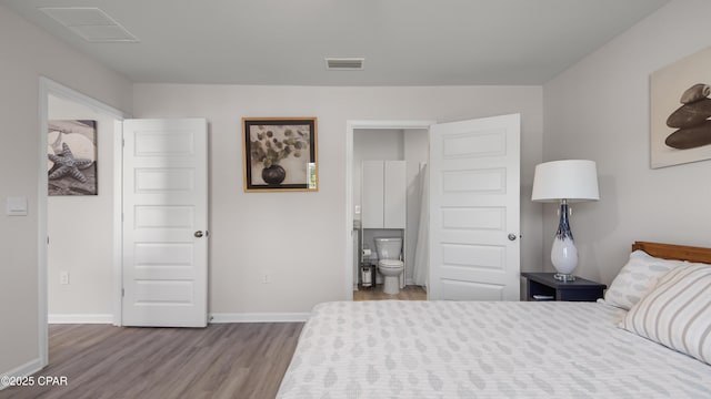 bedroom featuring baseboards, ensuite bathroom, wood finished floors, and visible vents