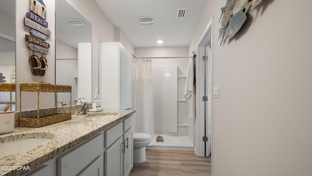 bathroom featuring visible vents, a shower stall, a sink, and wood finished floors