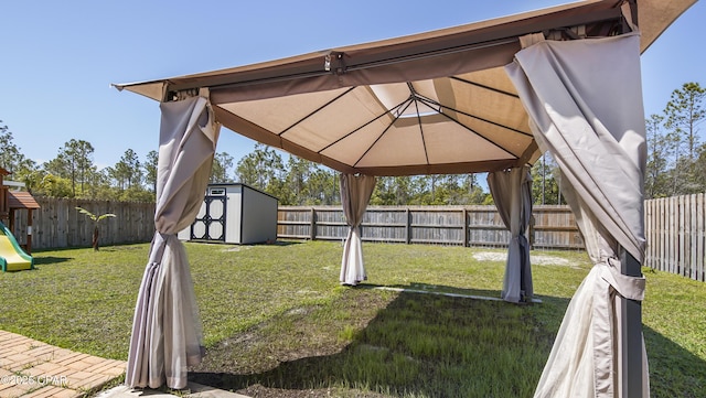 view of yard with a gazebo, a fenced backyard, a playground, and a storage unit