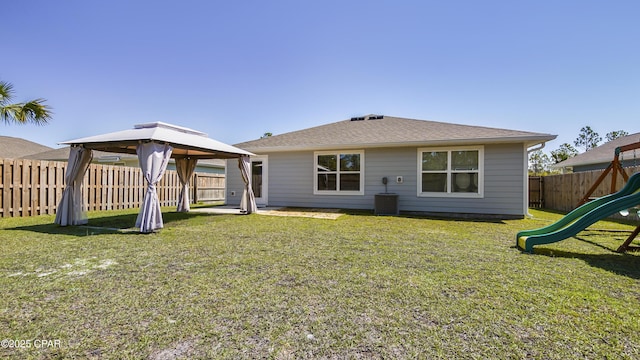 rear view of house with a yard, a gazebo, a fenced backyard, and a playground