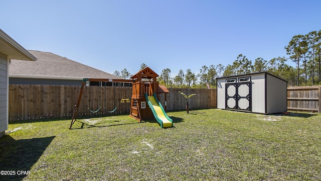 view of yard with an outbuilding, a fenced backyard, a playground, and a storage unit