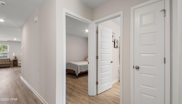 hall with baseboards, recessed lighting, and light wood-style flooring