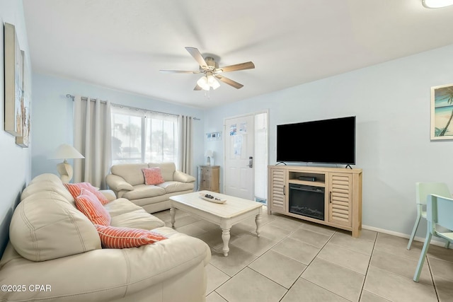 living area with a fireplace, a ceiling fan, baseboards, and light tile patterned floors