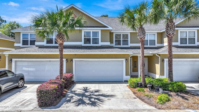 multi unit property featuring driveway, a shingled roof, a garage, and stucco siding