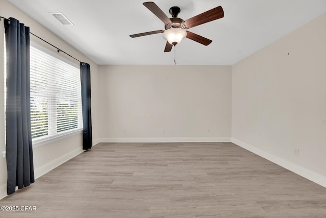 empty room with light wood finished floors, ceiling fan, baseboards, and visible vents