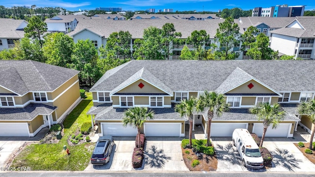 view of front of home featuring an attached garage, a residential view, driveway, and roof with shingles