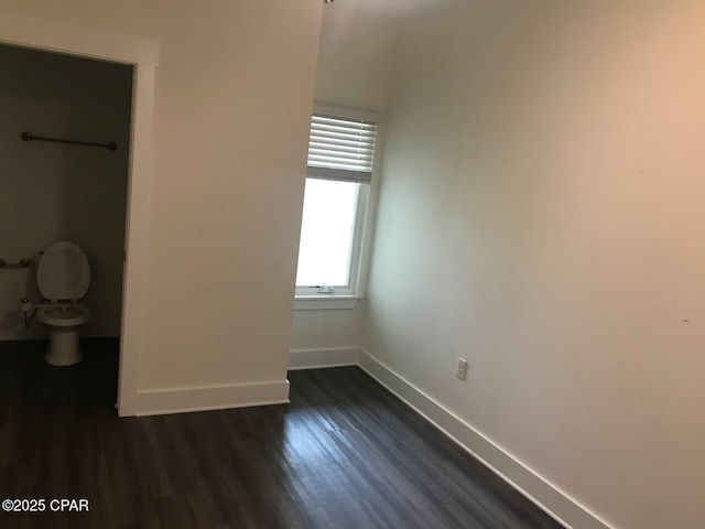unfurnished bedroom with baseboards and dark wood-style floors