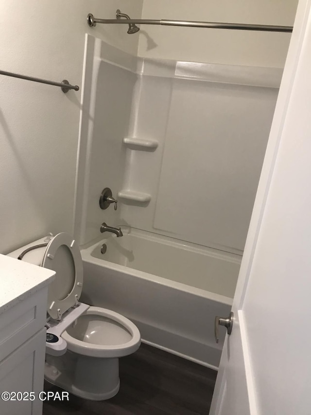 bathroom featuring toilet, vanity, wood finished floors, and shower / bathtub combination
