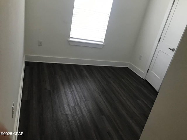 empty room featuring baseboards and dark wood-style floors