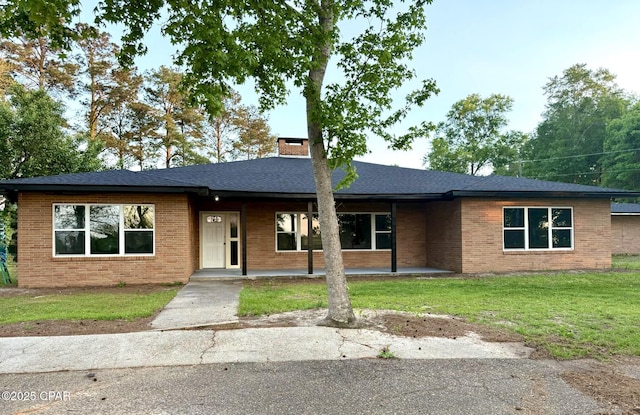 single story home with brick siding, a chimney, and a front lawn