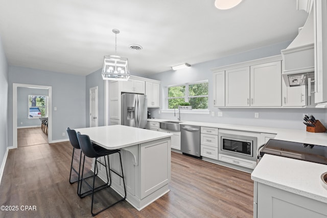kitchen featuring visible vents, a sink, a kitchen breakfast bar, stainless steel appliances, and a kitchen island