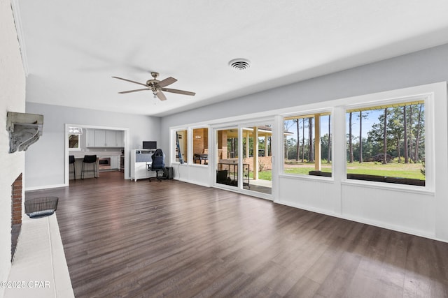 unfurnished living room with dark wood-style flooring, baseboards, a ceiling fan, and visible vents