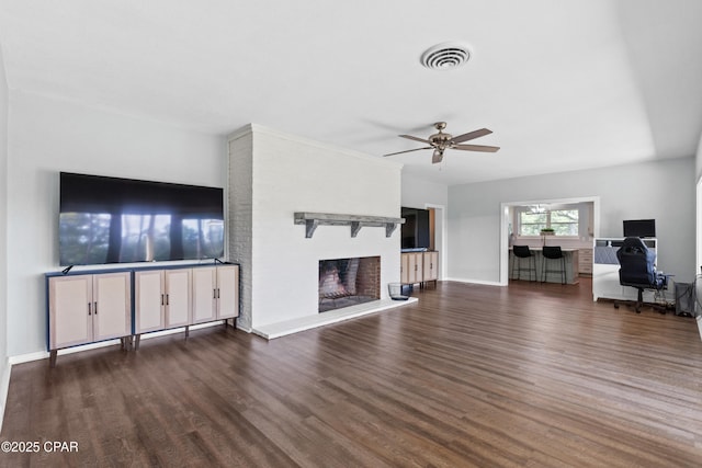 unfurnished living room with baseboards, a fireplace, a ceiling fan, visible vents, and wood finished floors