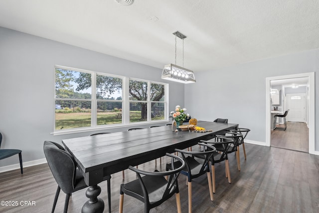 dining space featuring dark wood-type flooring and baseboards