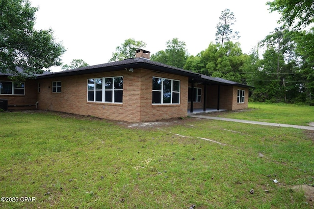 view of front facade featuring a patio area, a front lawn, a chimney, and brick siding
