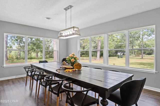 dining room featuring dark wood-style flooring, visible vents, baseboards, and a textured ceiling