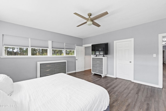 bedroom featuring ceiling fan, multiple windows, baseboards, and dark wood finished floors