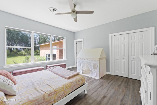 bedroom with a closet, a ceiling fan, visible vents, baseboards, and dark wood-style floors