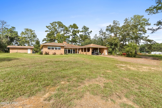 view of front of home featuring a carport, driveway, a chimney, and a front lawn