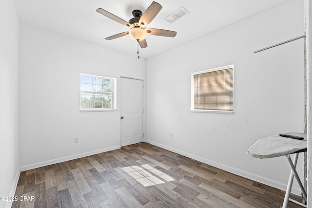 empty room featuring visible vents, baseboards, a ceiling fan, and wood finished floors