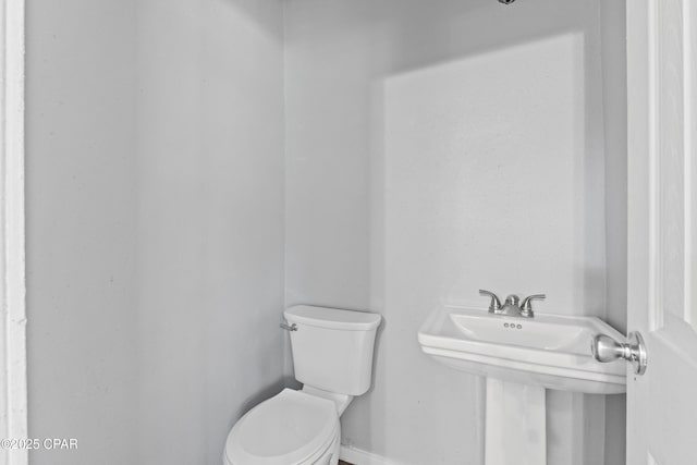 bathroom with baseboards, a sink, and toilet