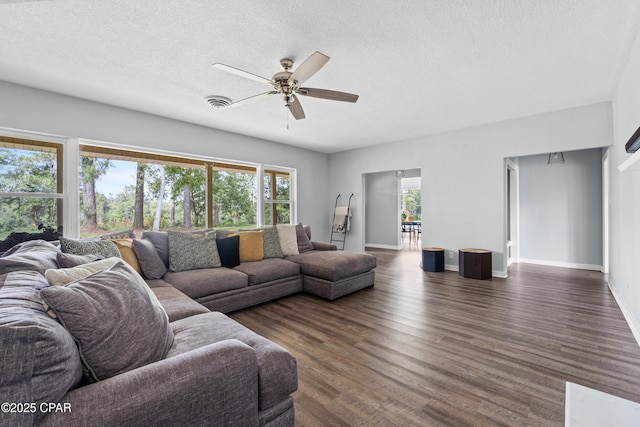 living area with dark wood-type flooring, a textured ceiling, ceiling fan, and baseboards