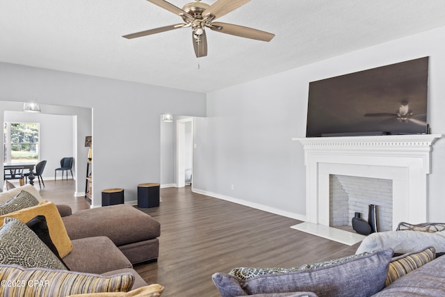 living area featuring dark wood finished floors, a fireplace with flush hearth, baseboards, and ceiling fan