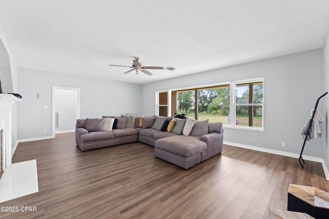 living room featuring dark wood-style flooring, ceiling fan, baseboards, and a fireplace