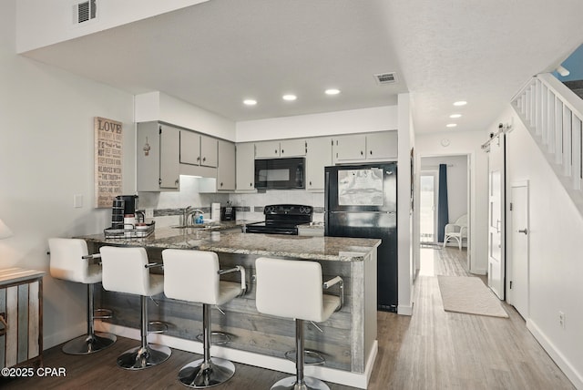 17670 Front Beach Rd Unit B8, Panama City Beach, FL 32413 - kitchen featuring black appliances, a peninsula, dark wood-style flooring, and visible vents