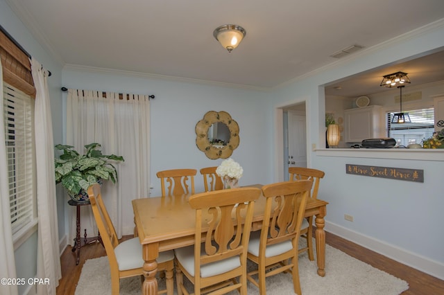 dining room featuring wood finished floors, visible vents, baseboards, and ornamental molding