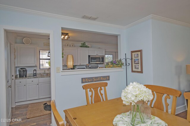 dining area with dark wood finished floors, visible vents, and crown molding