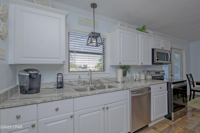kitchen featuring stainless steel appliances, a sink, white cabinetry, wood finished floors, and ornamental molding