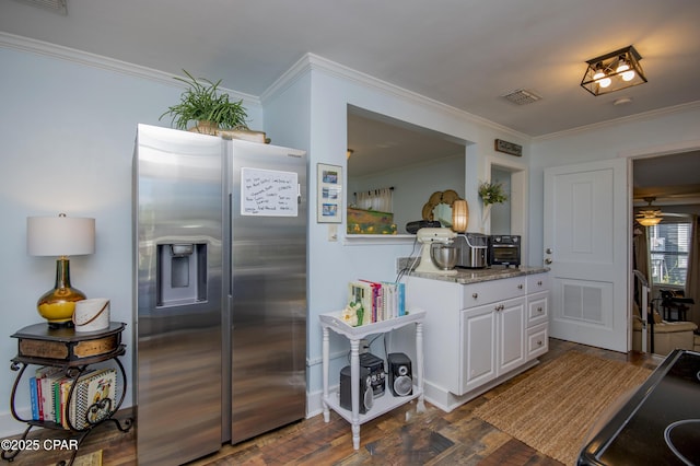 kitchen with stainless steel refrigerator with ice dispenser, visible vents, dark wood-style floors, and ornamental molding