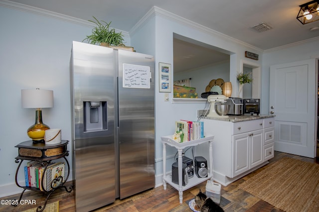 kitchen with wood finished floors, ornamental molding, stainless steel refrigerator with ice dispenser, white cabinetry, and visible vents