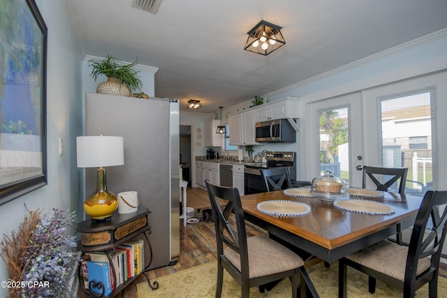 dining room with ornamental molding, light wood finished floors, and visible vents