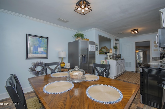 dining area with wood finished floors, visible vents, and ornamental molding