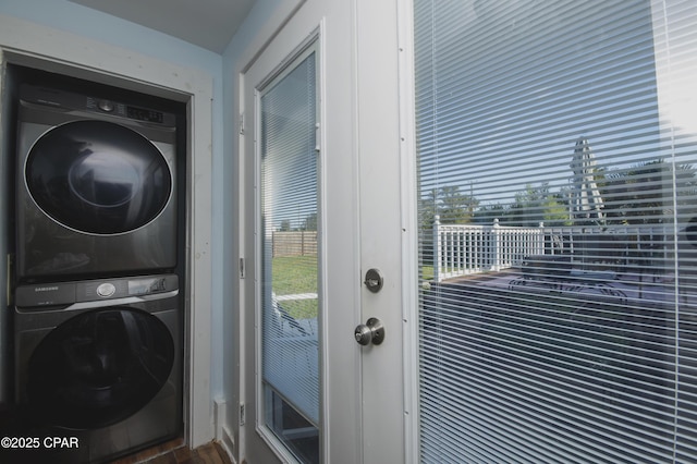 clothes washing area with stacked washer / dryer, wood finished floors, and laundry area