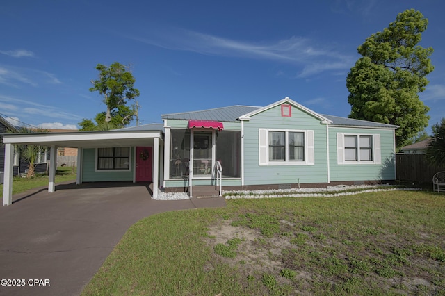 view of front facade featuring fence, driveway, an attached carport, a front yard, and metal roof