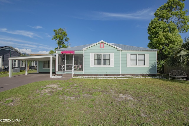 view of front of home featuring an attached carport, a front yard, driveway, and metal roof